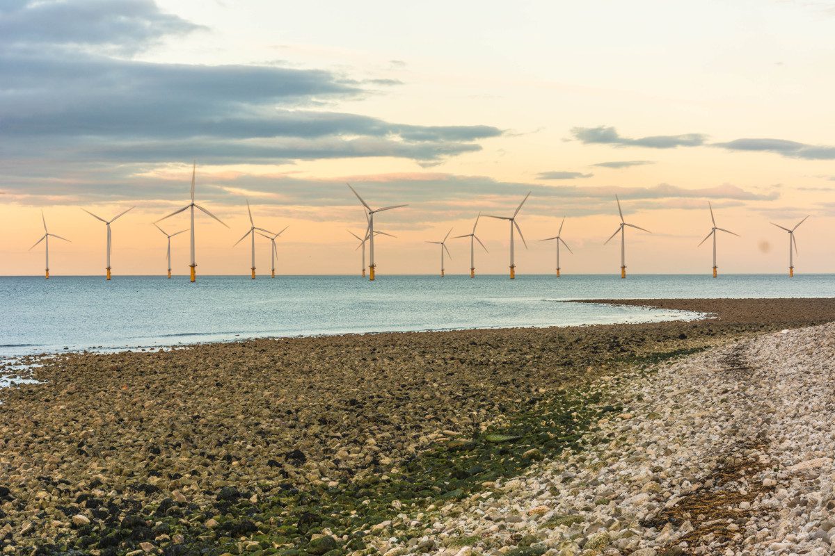 Wind turbines off UK coast with red sky in the distance
